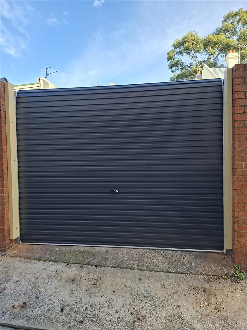 Charcoal roller door installed in a brick laneway garage in Sydney